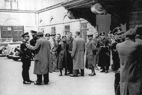 Bécs, 1938: Eichmann nem szerette, ha fényképezik. A Belügyminisztérium  udvarán gyanakodva nézi a fotóst (jobb szélen, feketében)